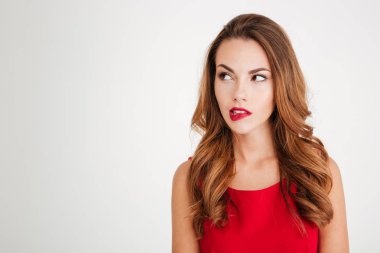 Unsure pretty young woman in red dress looking away clipart