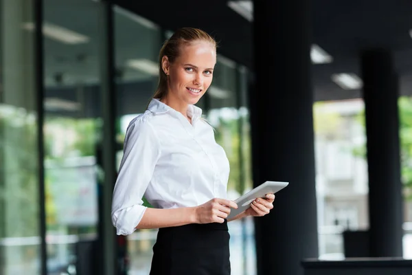 Businesswoman using digital tablet while standing at the glass railing — Stock Photo, Image