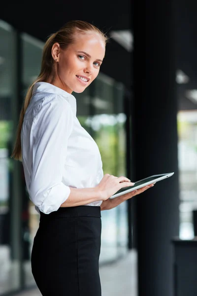 Portret van zakenvrouw met behulp van digitale tablet staande door glazen gebouw — Stockfoto