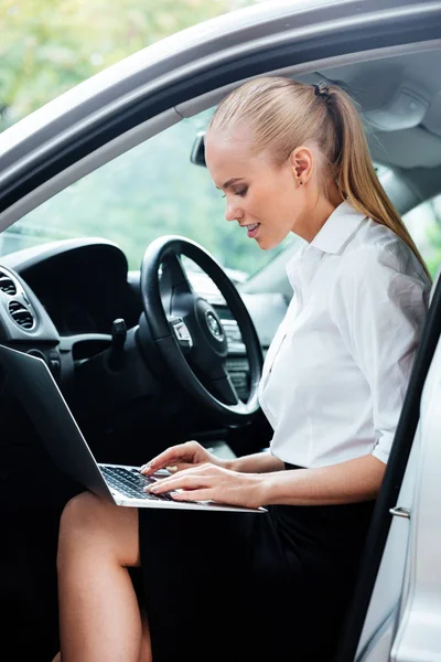 Affärskvinna med laptop medan du sitter i bilen och arbetar — Stockfoto