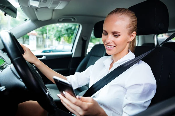 Smiling business woman dialing phone number while driving car — Stock Photo, Image