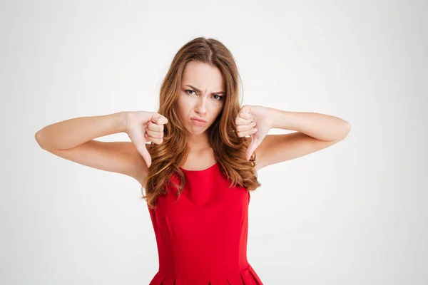 Portrait of upset woman in red dress showing thumbs down — Stok Foto