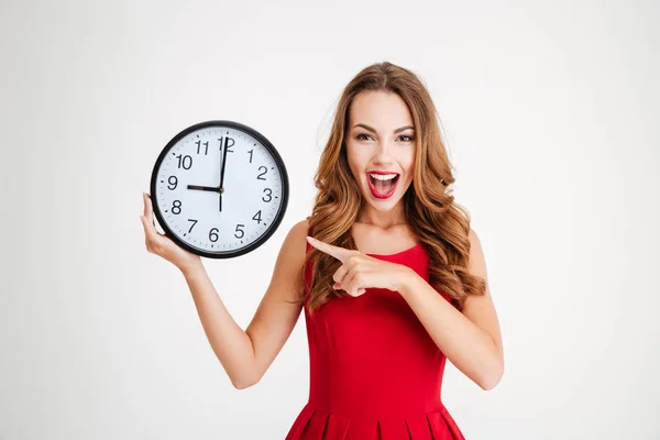 Frau im roten Weihnachtsmann-Kleid zeigt auf Wanduhr — Stockfoto