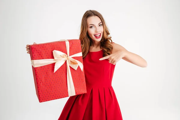 Femme en robe rouge pointant doigt à grande boîte cadeau — Photo