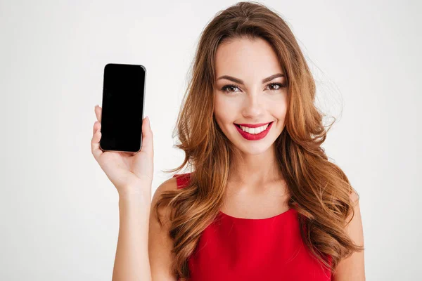 Mulher sorridente em vestido vermelho mostrando tela de smartphone em branco — Fotografia de Stock