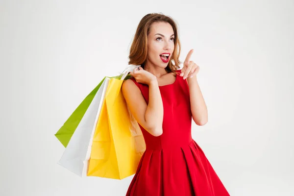 Encantadora mujer atractiva en vestido rojo sosteniendo bolsas de compras — Foto de Stock