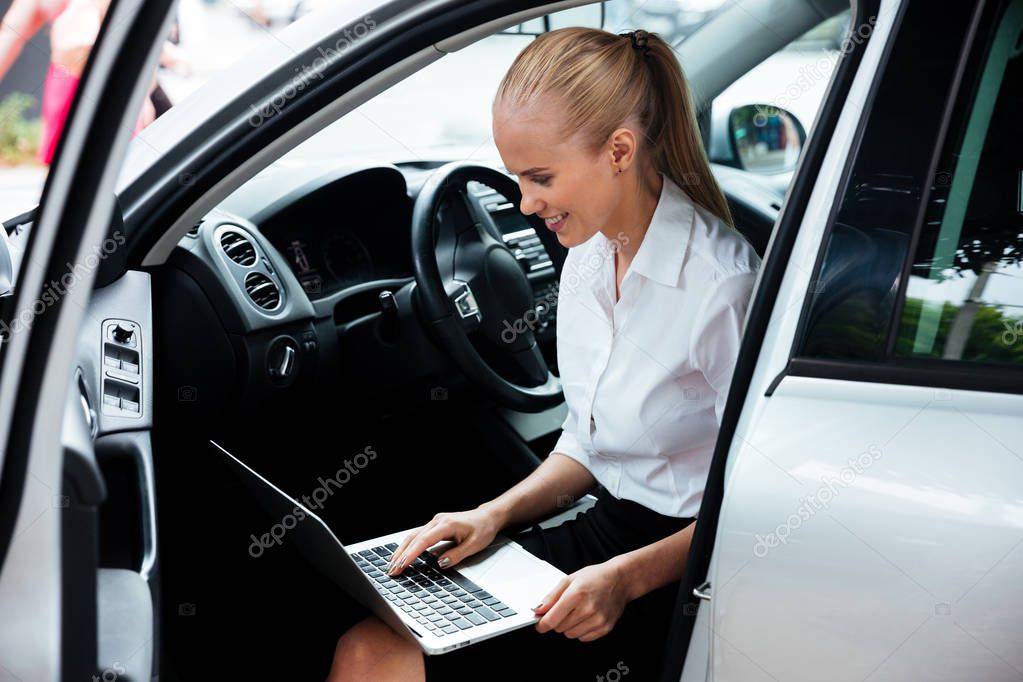 Businesswoman sitting in car and working with laptop