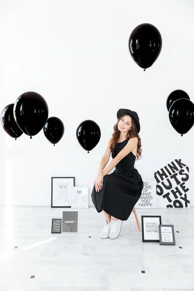Süslemeleri posterler ve balon ile yakın oturan neşeli kadın — Stok fotoğraf