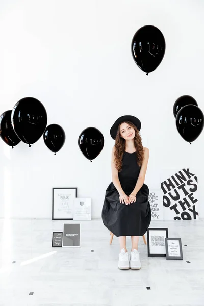 Posterler ve balon ile beyaz arka plan üzerinde oturan gülümseyen kadın — Stok fotoğraf