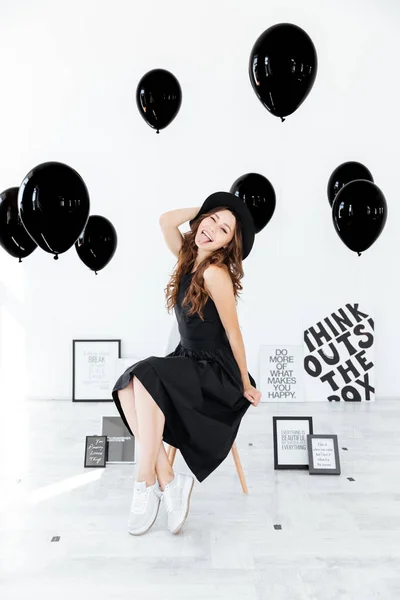 Playful young woman with posters and black balloons showing tongue — Stock Photo, Image