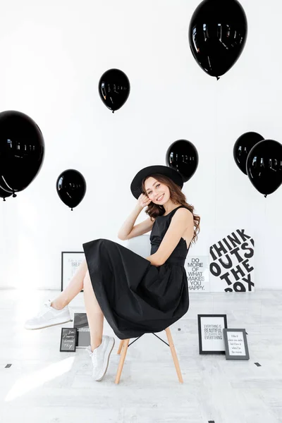 Posterler ve siyah balon ile oturan mutlu güzel genç kadın — Stok fotoğraf