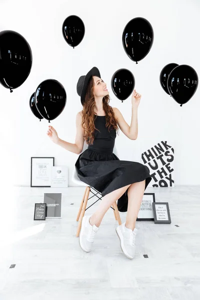 Oturma ve beyaz arka plan üzerinde siyah balon tutan kadın — Stok fotoğraf
