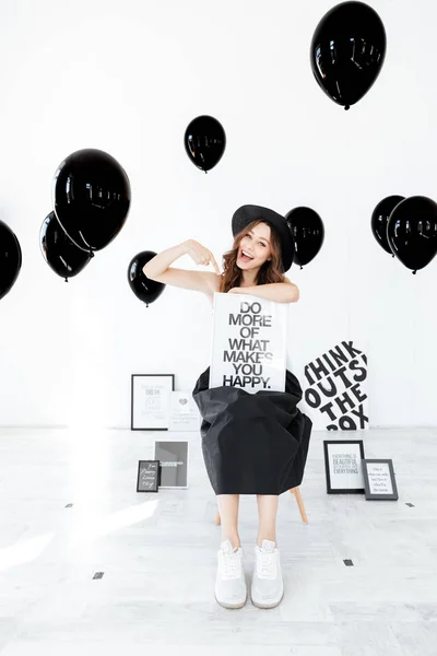 Veselá žena ukazující na plakátu nad bílým pozadím s balónky — Stock fotografie