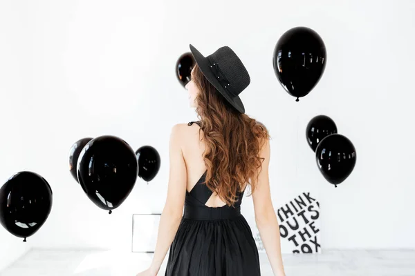Вид сзади женщины в черной шляпе с воздушными шарами — стоковое фото