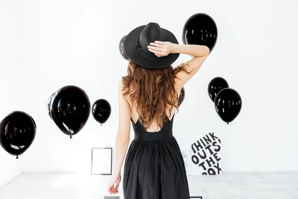 Hava balonları ile siyah şapkalı kadın arkadan görünüm — Stok fotoğraf