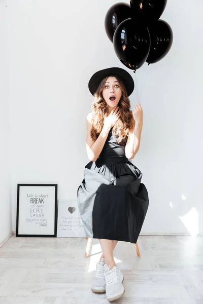 Sorprendido encantadora joven sosteniendo globos negros —  Fotos de Stock