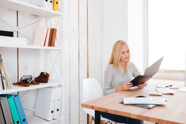 Mujer de negocios sosteniendo carpeta mientras está sentada en su lugar de trabajo — Foto de Stock