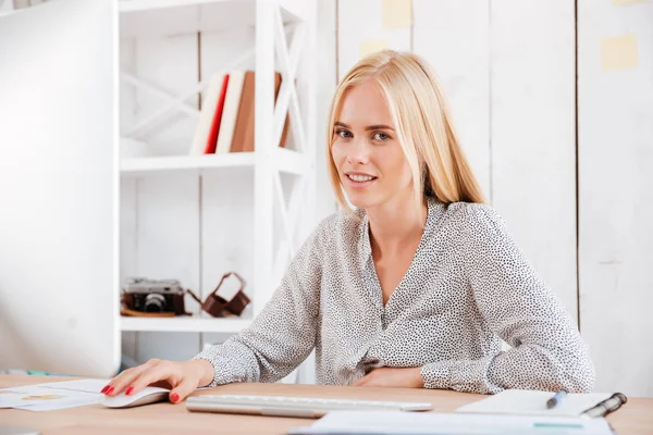Χαμογελαστή γυναίκα κάθεται στο χώρο εργασίας και να χρησιμοποιούν τον υπολογιστή — Φωτογραφία Αρχείου