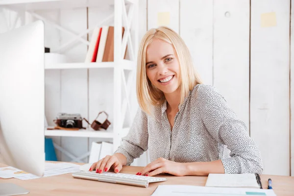 Щаслива молода бізнес-леді сидить з комп'ютером в офісі — стокове фото