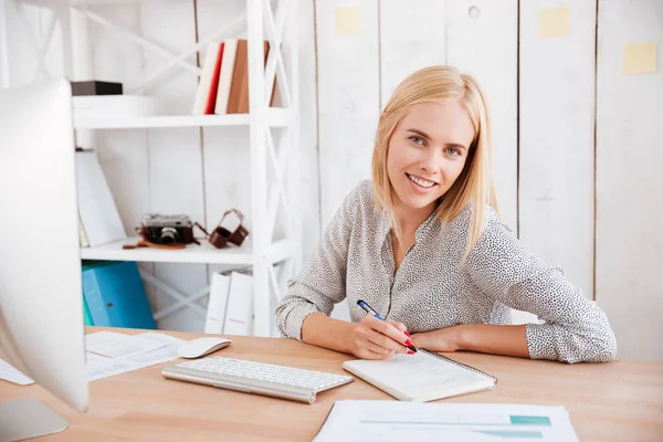 Bizneswoman siedzi w miejscu pracy i robi notatki — Zdjęcie stockowe