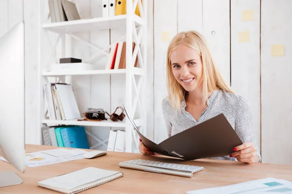 彼女の職場でフォルダーを開くを保持している若いブロンドの女性 — ストック写真