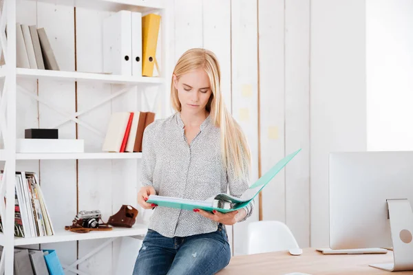 Mujer de negocios sentada en su lugar de trabajo y mirando documentos — Foto de Stock