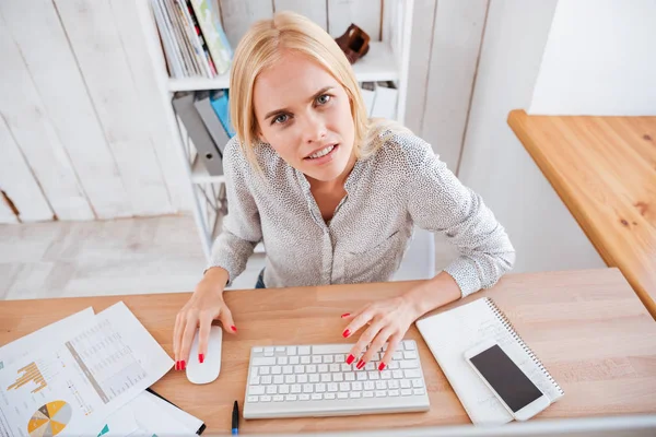 Mulher loira frustrada trabalhando no computador e olhando para a câmera — Fotografia de Stock