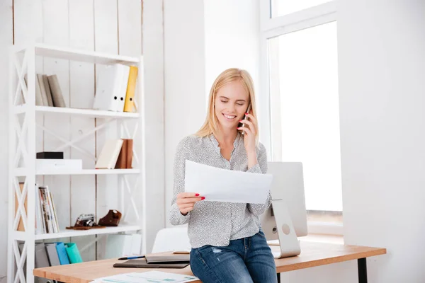 Sonriente mujer feliz hablando en el teléfono móvil y sosteniendo el documento — Foto de Stock