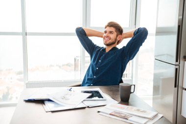 Tablo oturan ve evde germe neşeli genç adam