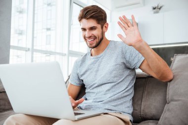 Neşeli adam laptop arıyorum ve gülümseyen sallayarak