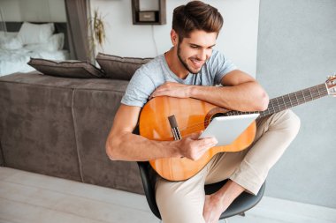 Gitar ile oturma ve tablete arıyorum genç adam