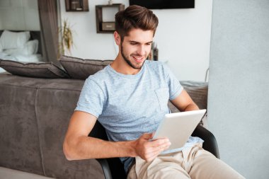Sandalyede oturan ve tablet tutan genç gelin adam