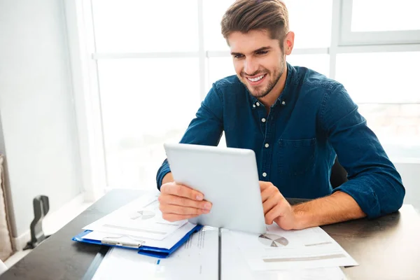 Glad ung man analysera ekonomi hemma och hålla tablett — Stockfoto