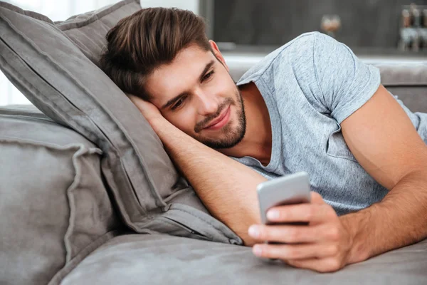Ung man chattar medan du ligger på soffan — Stockfoto