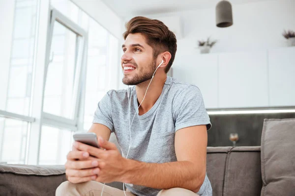 Boldog ember, zenét hallgatni, miközben ül a kanapén — Stock Fotó