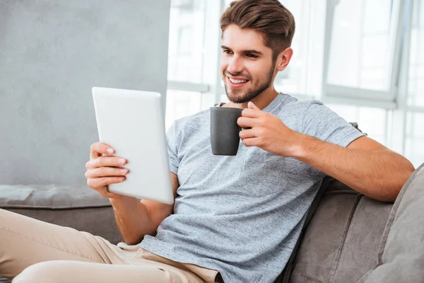 Hombre alegre comunicación por tableta mientras bebe un café — Foto de Stock