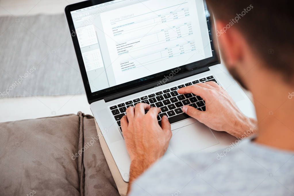 Cropped image of man typing by laptop. Focus on hands