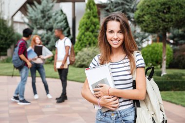 Neşeli kadın öğrenci kampus içinde sırt çantası konumu olan