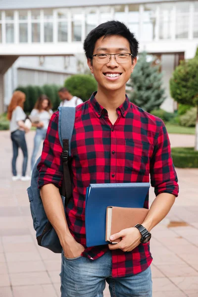Щасливий азіатський молодий студент з рюкзаком, що стоїть на відкритому повітрі — стокове фото