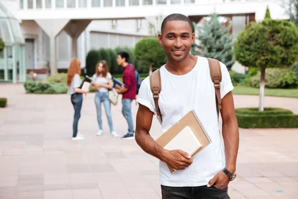 Sorrindo estudante homem africano com mochila em pé ao ar livre — Fotografia de Stock