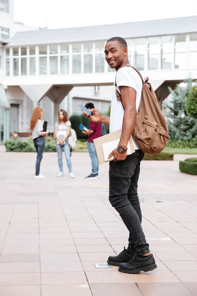 Sonriente estudiante africano con mochila caminando en el campus — Foto de Stock