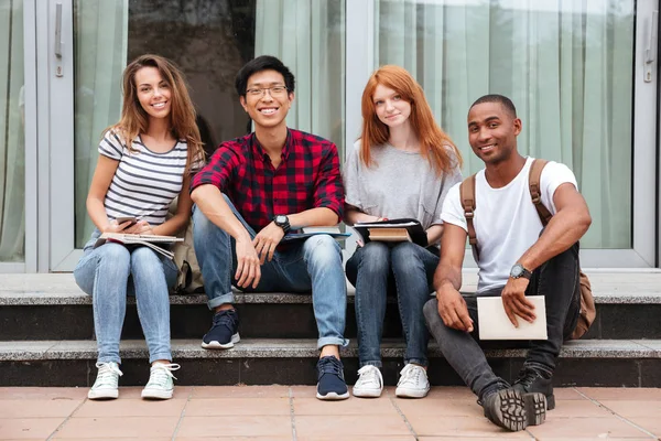 Glückliche junge Leute sitzen zusammen auf dem Campus — Stockfoto