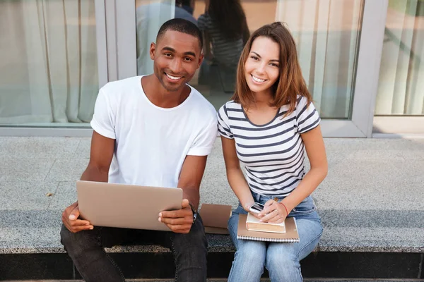 Casal sorrindo usando laptop ao ar livre juntos — Fotografia de Stock