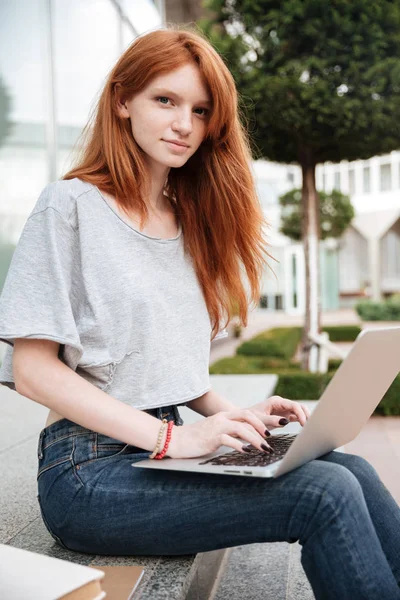 Piękna kobieta siedzi i za pomocą laptopa na zewnątrz — Zdjęcie stockowe