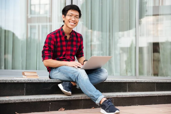 Feliz asiático joven hombre usando laptop al aire libre —  Fotos de Stock