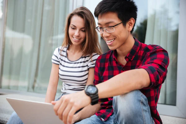 Glückliches Paar, das zusammen im Freien sitzt und Laptop benutzt — Stockfoto