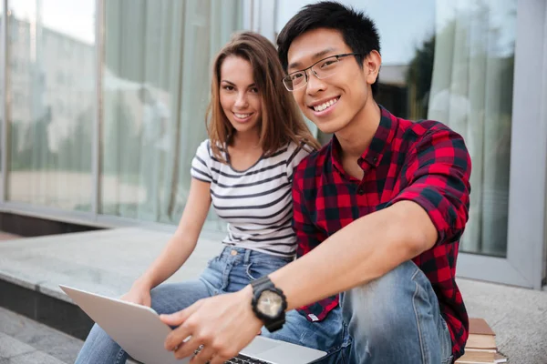 Vrolijke paar praten en het gebruik van laptop samen buiten — Stockfoto