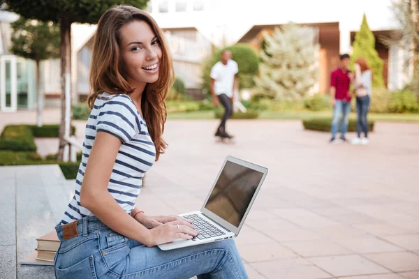 Sorridente giovane donna carina che lavora con il computer portatile all'aperto — Foto Stock