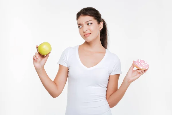 Woman choosing between donut and apple — Stock Photo, Image