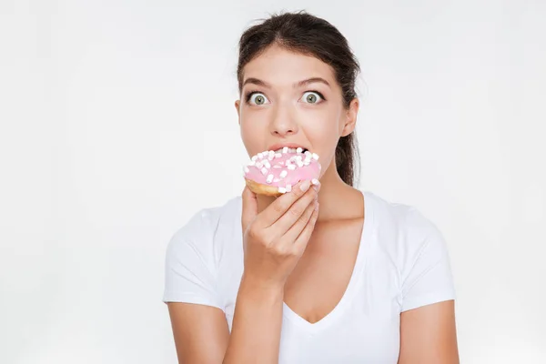 Confused diet young woman eating tasty donut — Stock Photo, Image